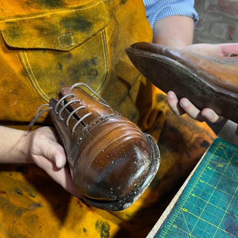 Assessment of a worn brown leather brogue at the Spitshine workshop — the first step of the seven-step shoe care service